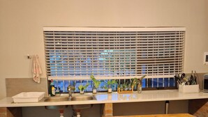 A kitchen with a wooden countertop, a sink, a window with blinds, and a hanging light fixture.
