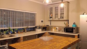 A kitchen with a central island, overhead pendant lights, a microwave, a toaster, and a refrigerator.
