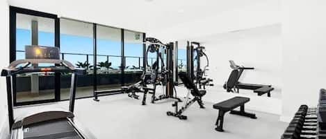 A modern gym with a treadmill, weight machines, and a bench.