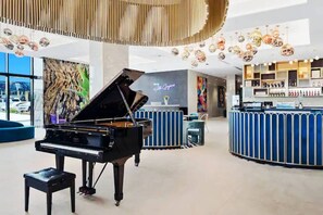 A grand piano in a spacious lobby with a modern bar area and a colorful mural on the wall. - Luxury apartment perfect for holidays on the coast (Southport)