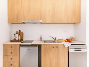 A kitchen with wooden cabinets, a dishwasher, a sink, and a countertop with kitchen essentials. - One-Bedroom Apartment for 2 with Garden View (Molos)