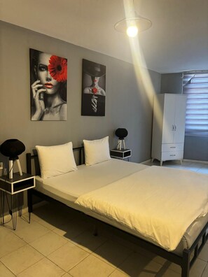 Une chambre à coucher bien rangée, avec un lit, des tables de chevet, une armoire et deux œuvres d’art accrochées au mur.