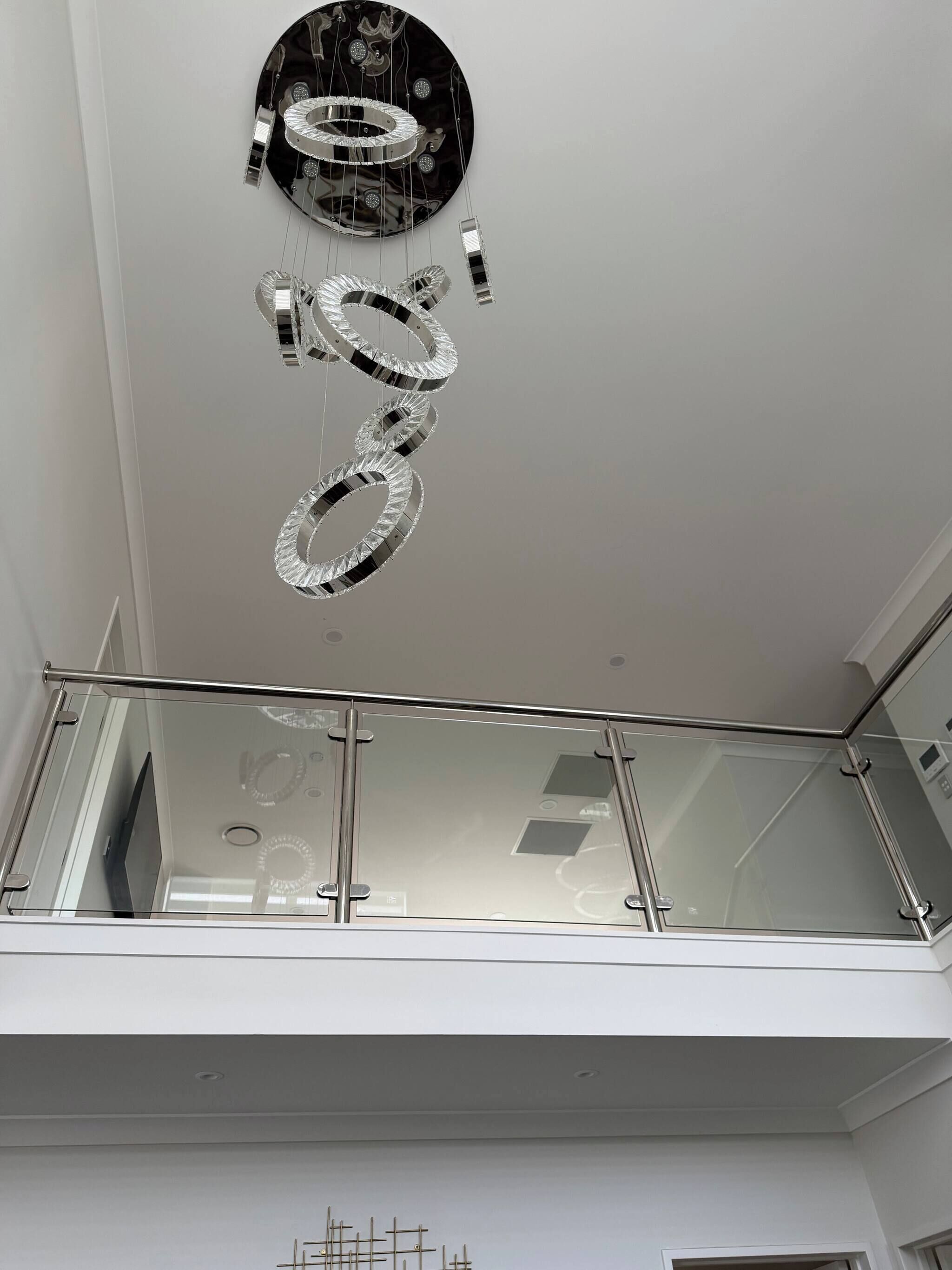 A modern interior with a reflective ceiling fixture and a glass railing.
