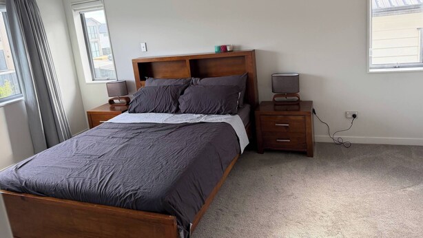 A bedroom with a wooden bed, bedside tables, a lamp, and a window.