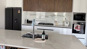 A modern kitchen with a marble countertop, stainless steel appliances, and wooden cabinets.