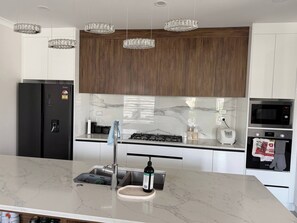 A modern kitchen with a marble countertop, stainless steel appliances, and wooden cabinets.
