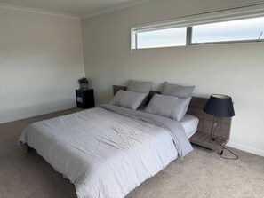 A bedroom with a bed, a bedside table, a lamp, and a window.