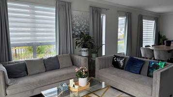 Una sala de estar moderna con dos sofás, una mesa de centro de vidrio y vistas al exterior.