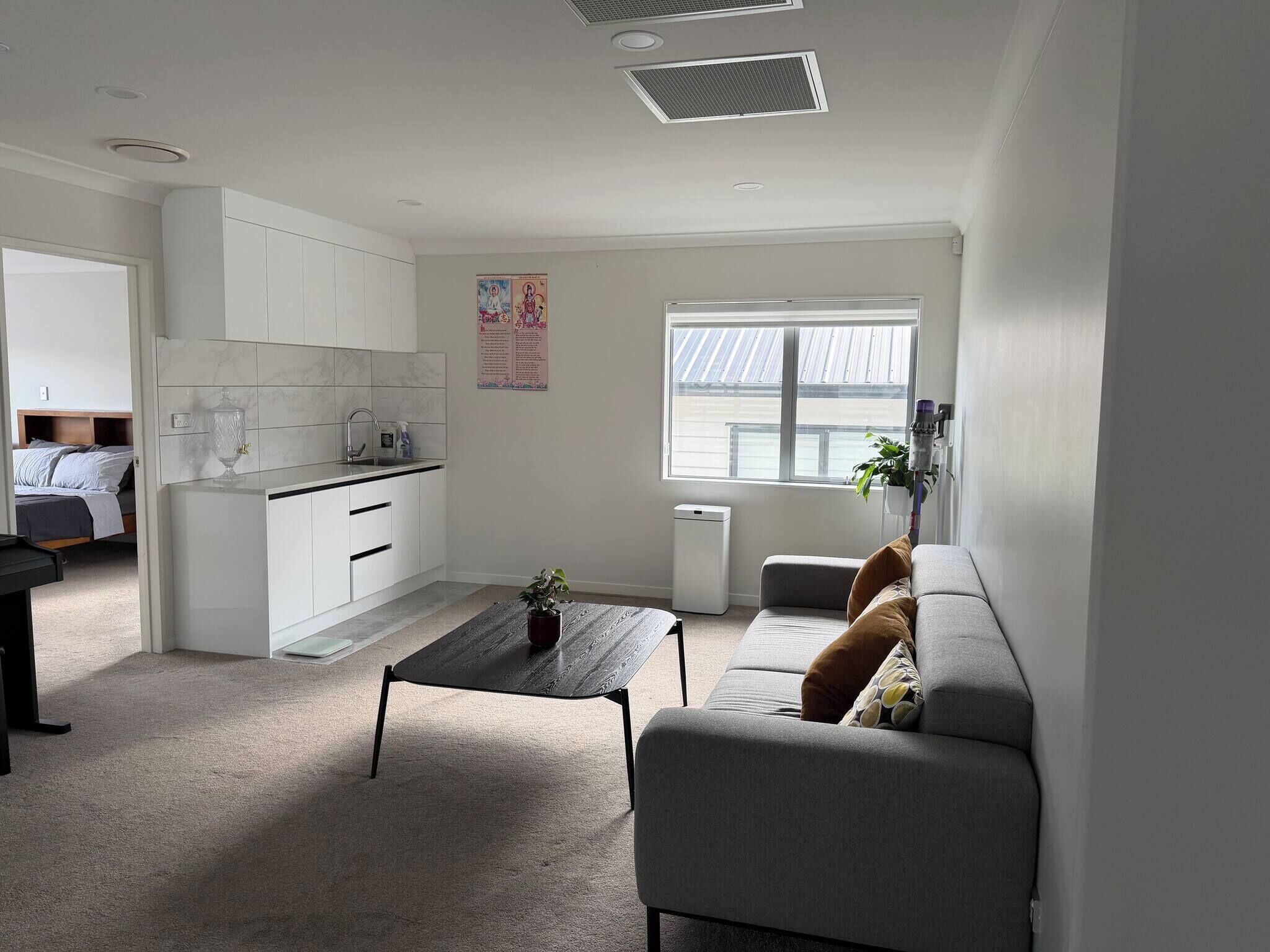 A compact living space with a kitchenette, a sofa, a small table, and a window.