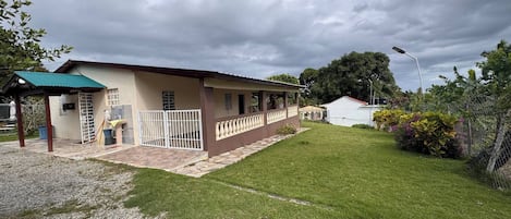 Un edificio de dos pisos con un porche cubierto y un patio cercado.
