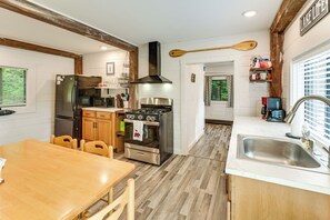 A kitchen with a stove, oven, refrigerator, wooden cabinets, and a dining table.