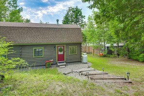 A log cabin with a red door, a chimney, and a small porch. - Paddle, Fish & Stargaze: Peaceful Lincoln Escape (Lincoln)