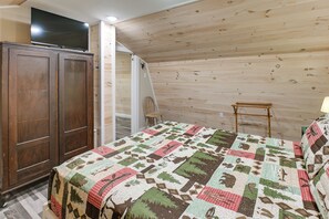 A bedroom with a wooden ceiling, a bed with a patterned quilt, a wooden wardrobe, and a chair. - Paddle, Fish & Stargaze: Peaceful Lincoln Escape (Lincoln)