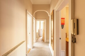 A hallway with a radiator, a fire blanket, and a telephone on the wall. - Incredibly Located 3BDR Flat in Edinburgh (Edinburgh)