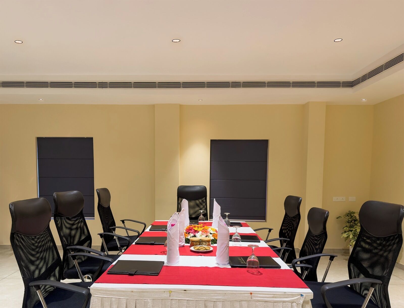 A conference room with a long table, black chairs, and a red tablecloth.