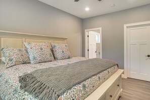 Une chambre à coucher avec un lit, des oreillers, une table de chevet et une porte.