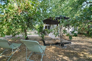 An outdoor seating area with a table and chairs, surrounded by trees.