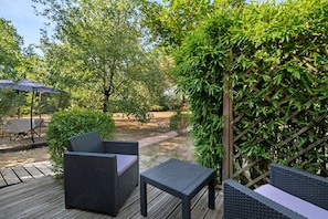 An outdoor patio area with wicker furniture and a wooden deck. - Bed and Breakfast 'Chambre D'hôtes Les Coquelicots' with Private Terrace, Wi-Fi and Air Conditioning (Fronton)