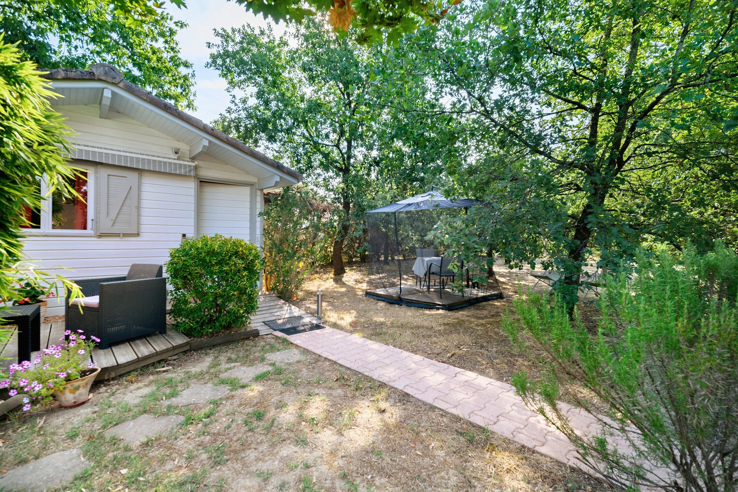 A residential property with a covered patio area, a small deck, and a house with a garage.