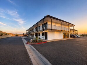 A two-story hotel with a flat roof, multiple balconies, and a parking lot.