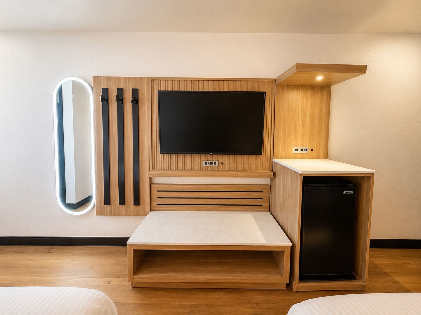 A modern room with a built-in TV, a small kitchenette, and a bedside table.