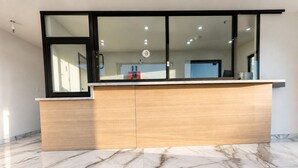 A reception desk with a glass partition, marble flooring, and a modern interior design.