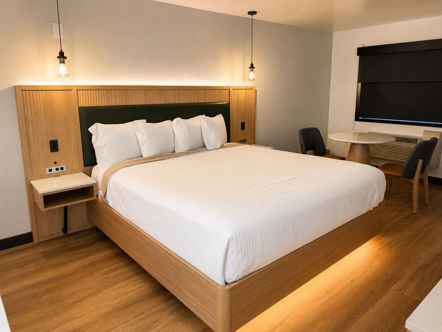 Une chambre d’hôtel moderne, dotée d’un grand lit, de tables de chevet, d’un bureau et d’une chaise.