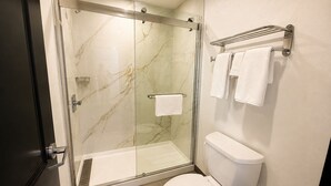 A modern bathroom with a glass-enclosed shower, a toilet, and a towel rack.