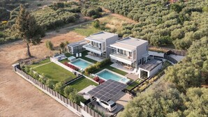 A modern two-story house with a swimming pool, solar panels, and a fenced yard.