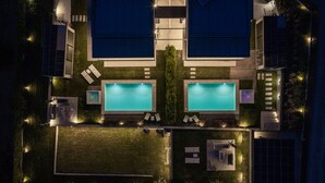 Uma área de piscina no terraço com duas piscinas, espreguiçadeiras e uma banheira de hidromassagem.
