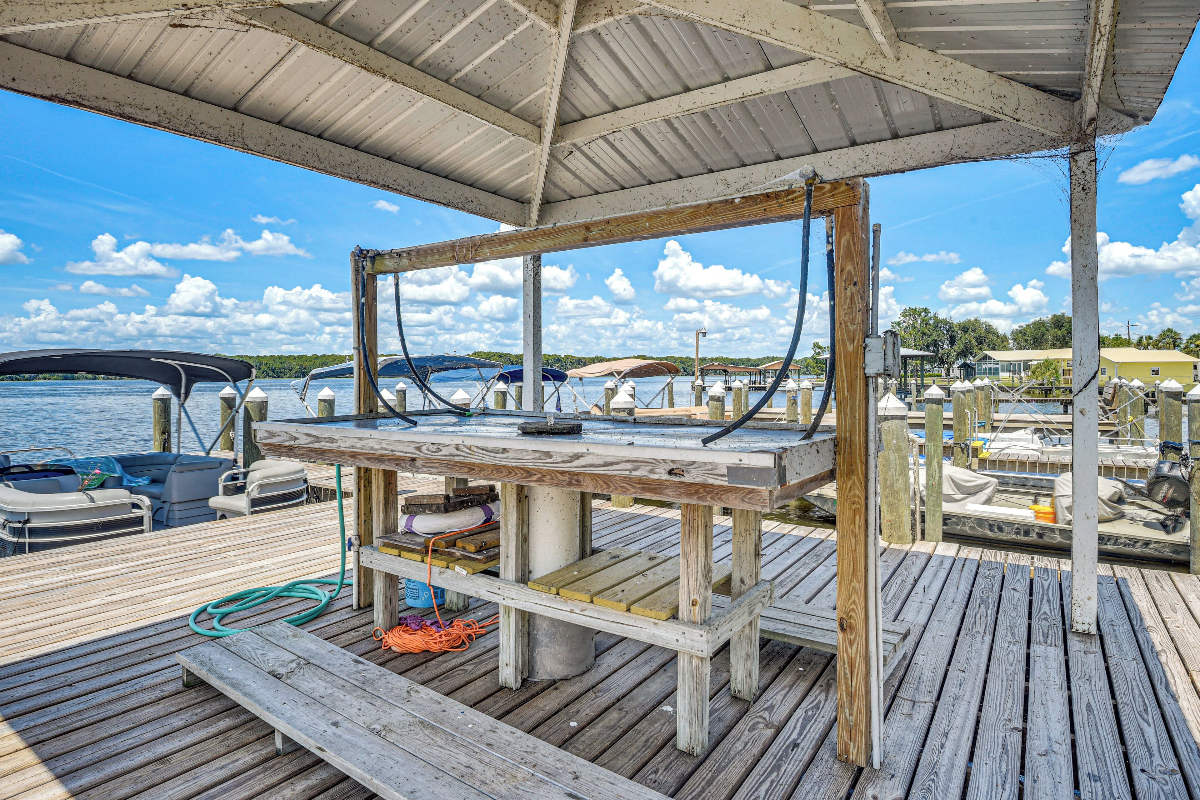 A wooden dock with a covered seating area, boats, and a clear view of the water.