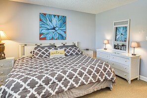 A bedroom with a bed, two nightstands, a dresser, and a large floral painting on the wall. - Boat Dock, Slips & Pool! St Johns River Condo (Welaka)
