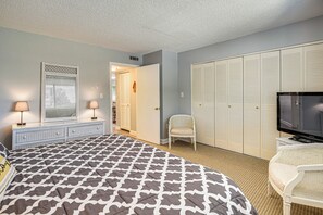 A bedroom with a bed, a television, a chair, a wardrobe, and a window with blinds. - Boat Dock, Slips & Pool! St Johns River Condo (Welaka)
