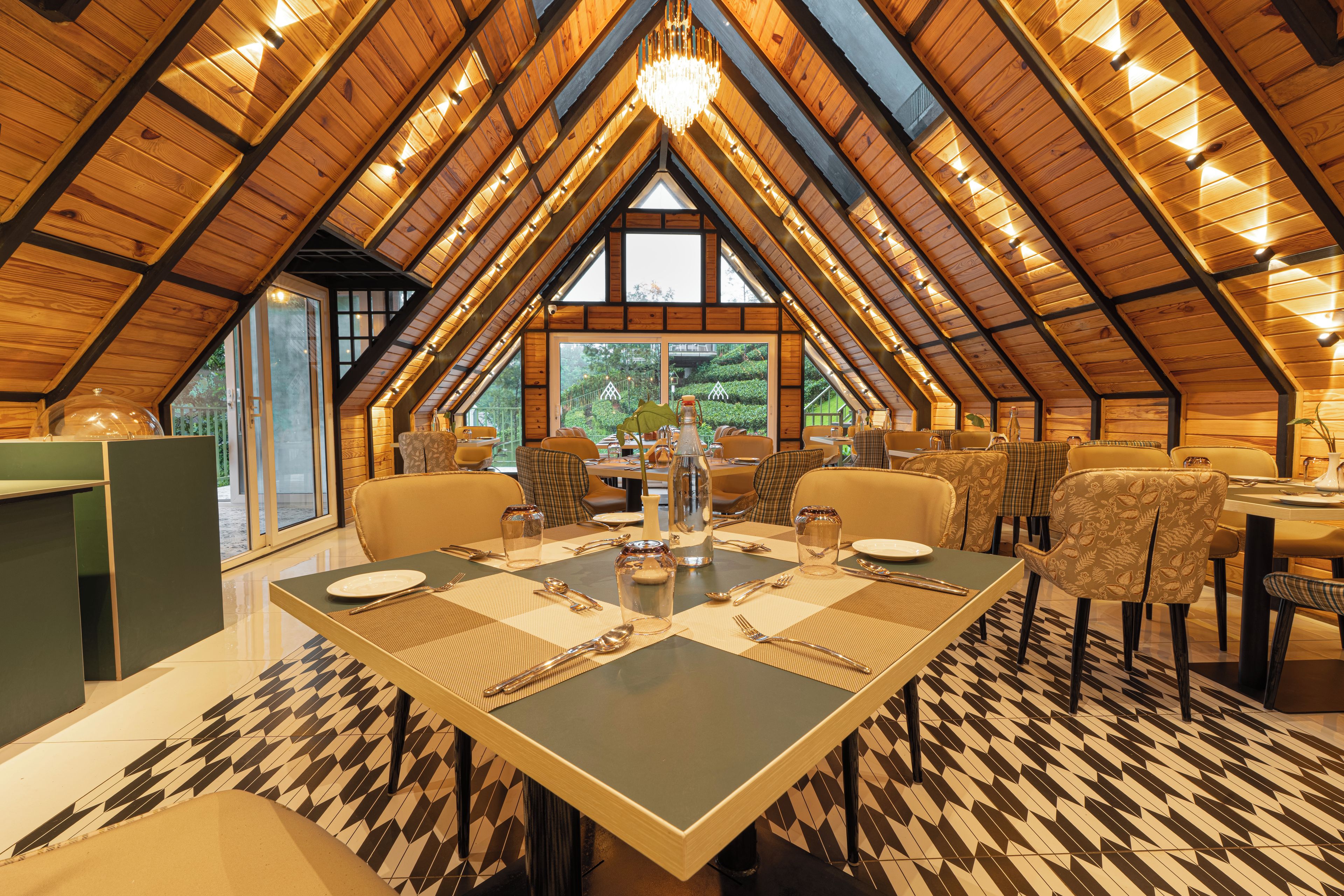 A dining area with a high ceiling and wooden beams, featuring a large table set for four with chairs.