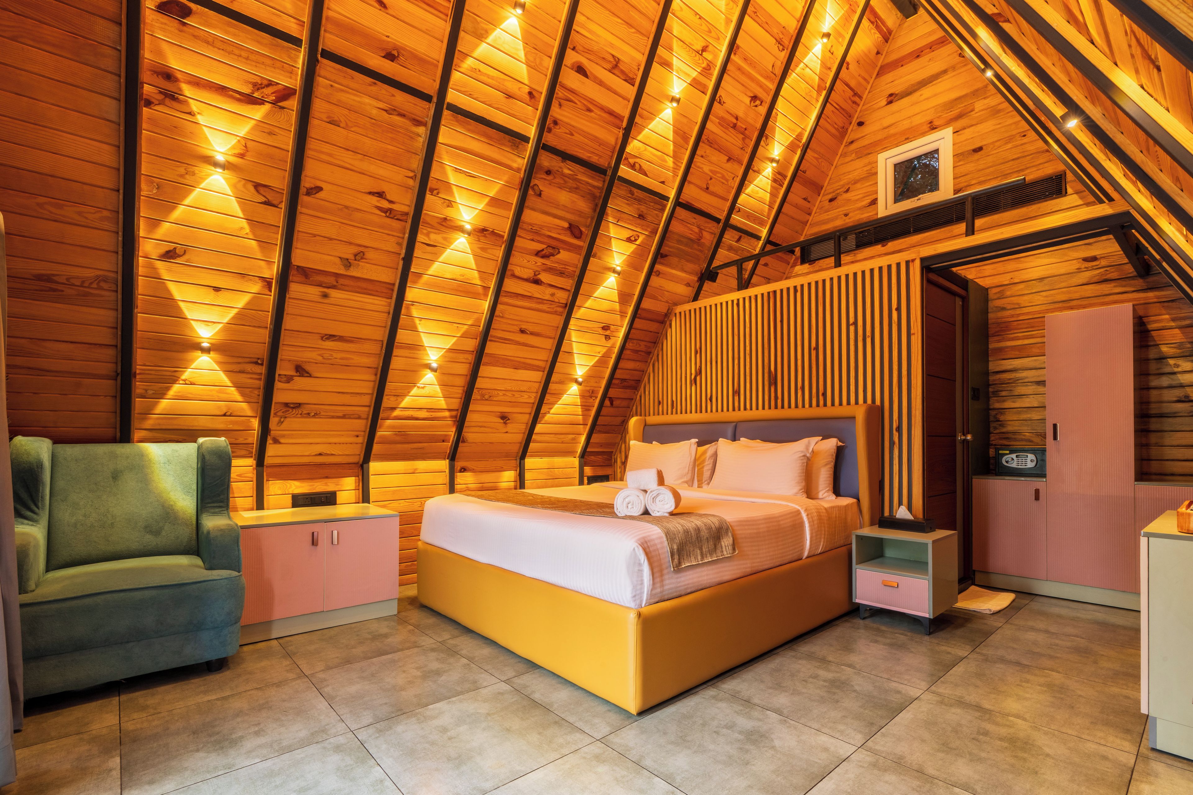 A bedroom with a sloped ceiling, a bed, a chair, and a small cabinet.