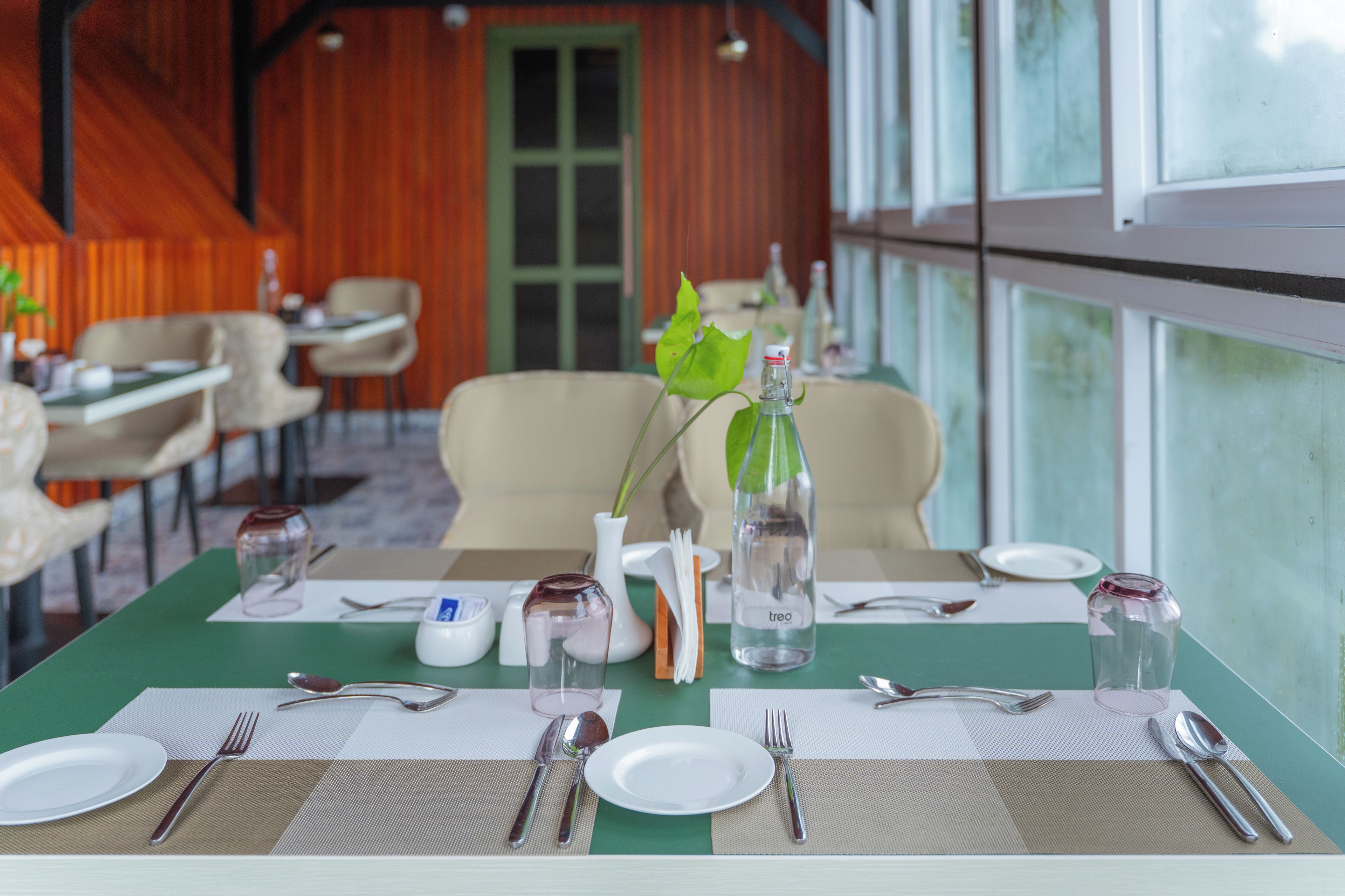 Une table à manger dressée avec des assiettes, des couverts et une bouteille d’eau.