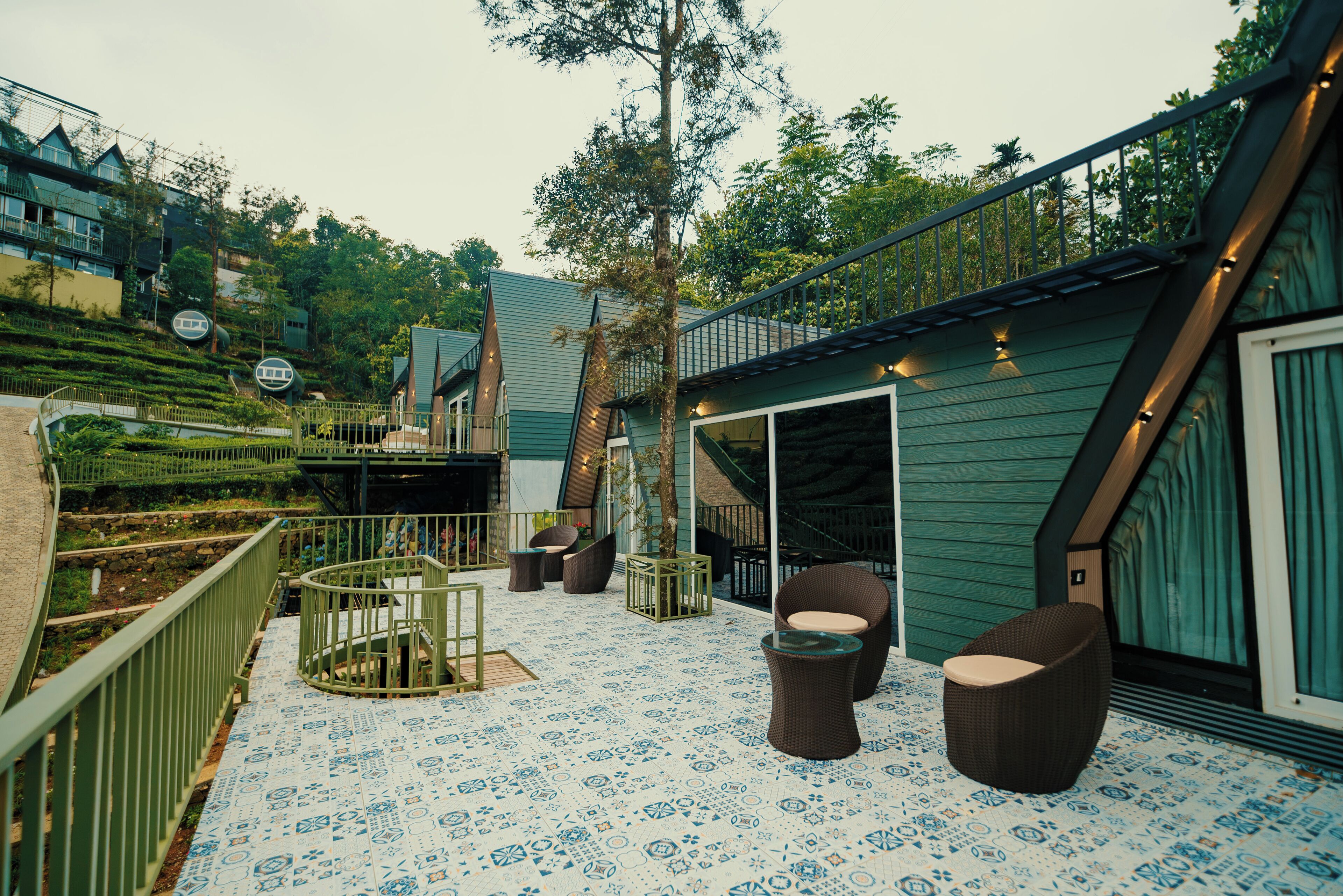 A terrace with outdoor seating, a staircase, and a view of a hillside.