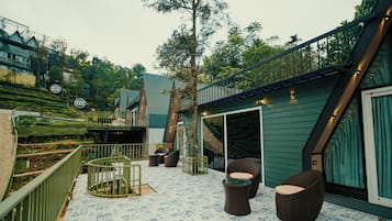 A terrace with outdoor seating, a staircase, and a view of a hillside.