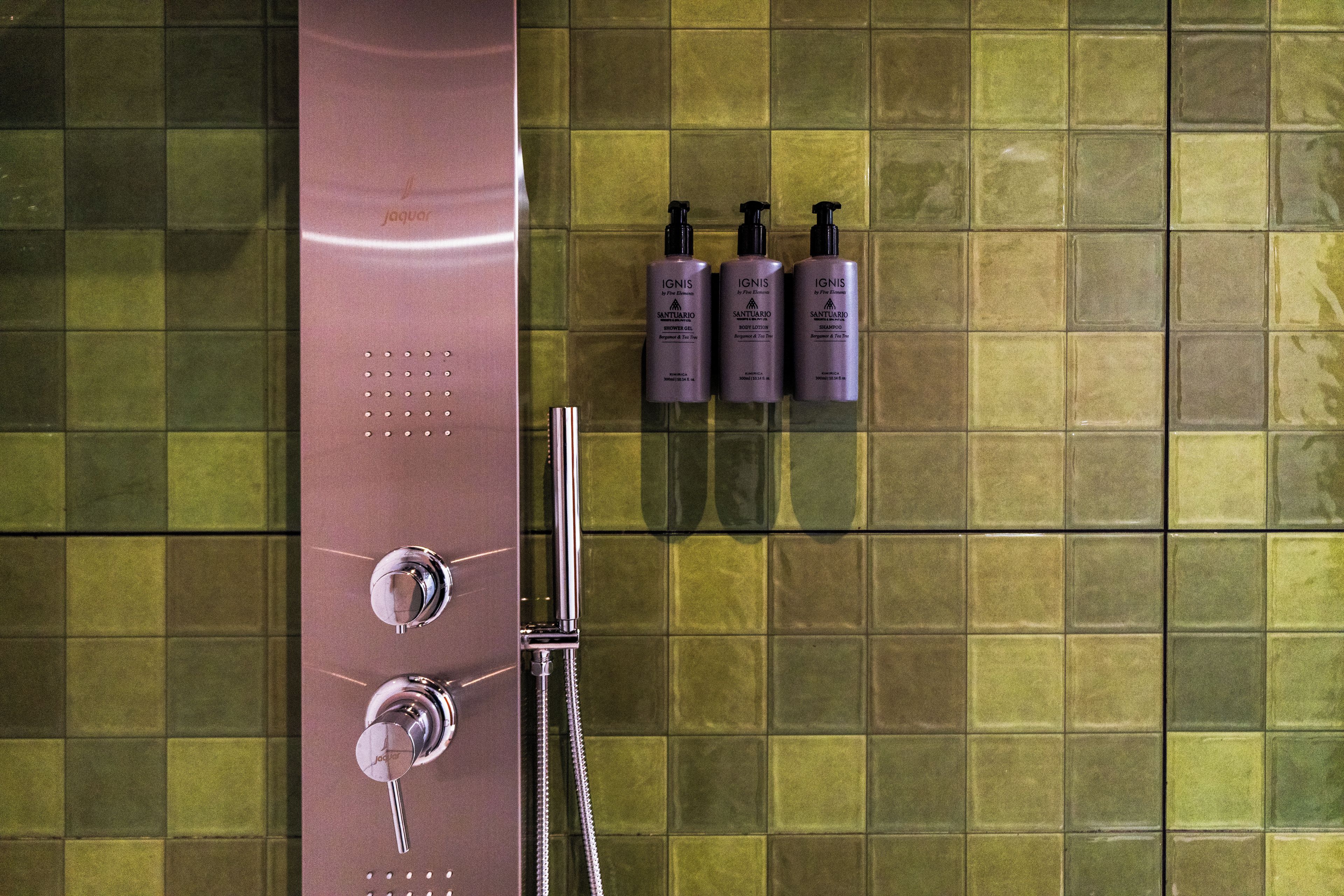 Un baño con ducha, perchero y tres botellas de champú.