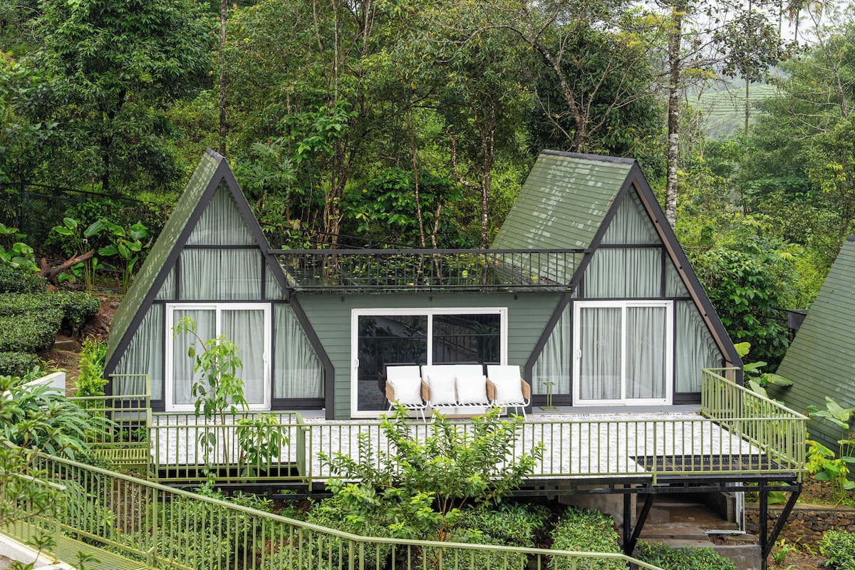 A cabin with a balcony, surrounded by dense forest.