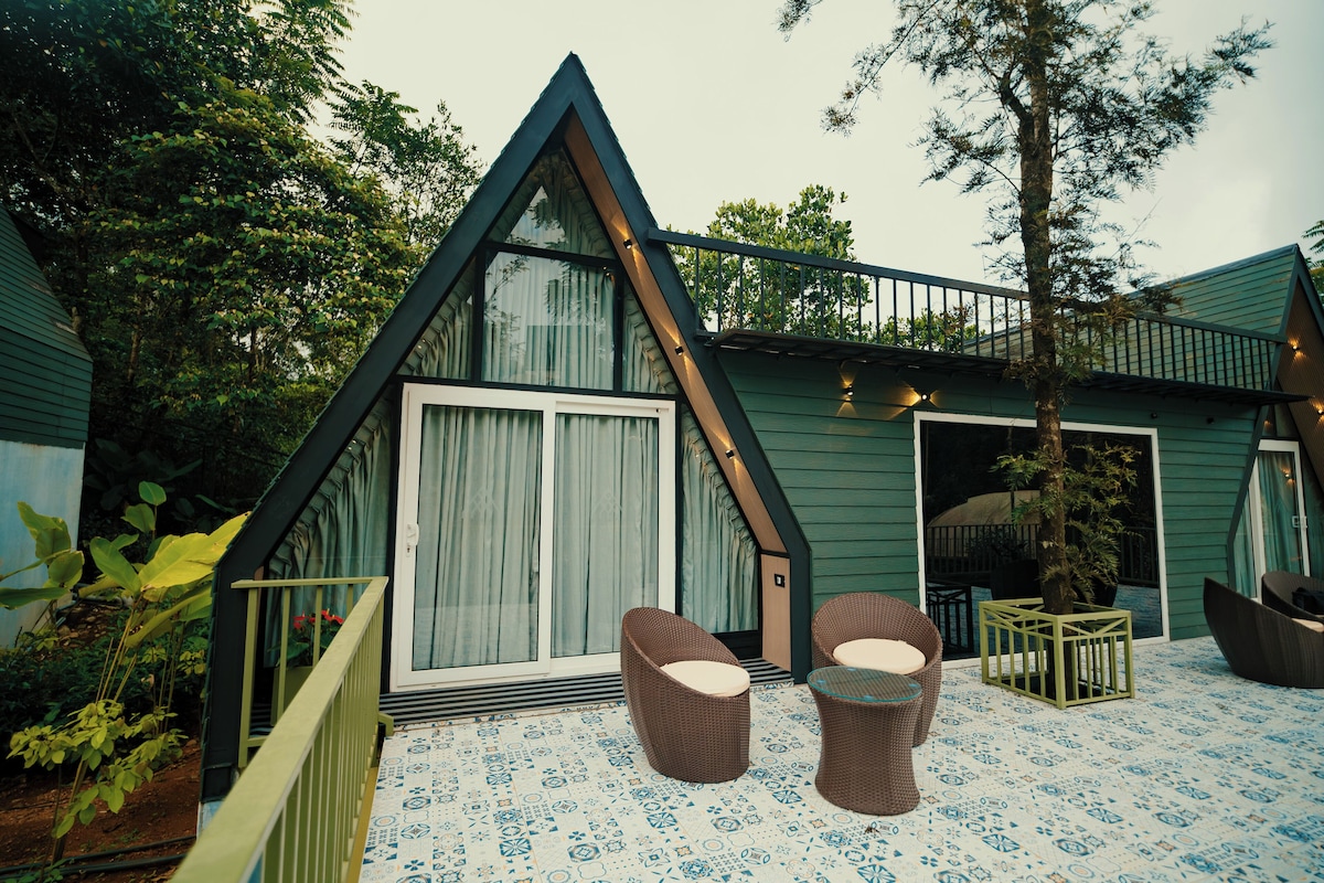 A triangular-shaped building with a large sliding door, two wicker chairs, and a patterned floor.