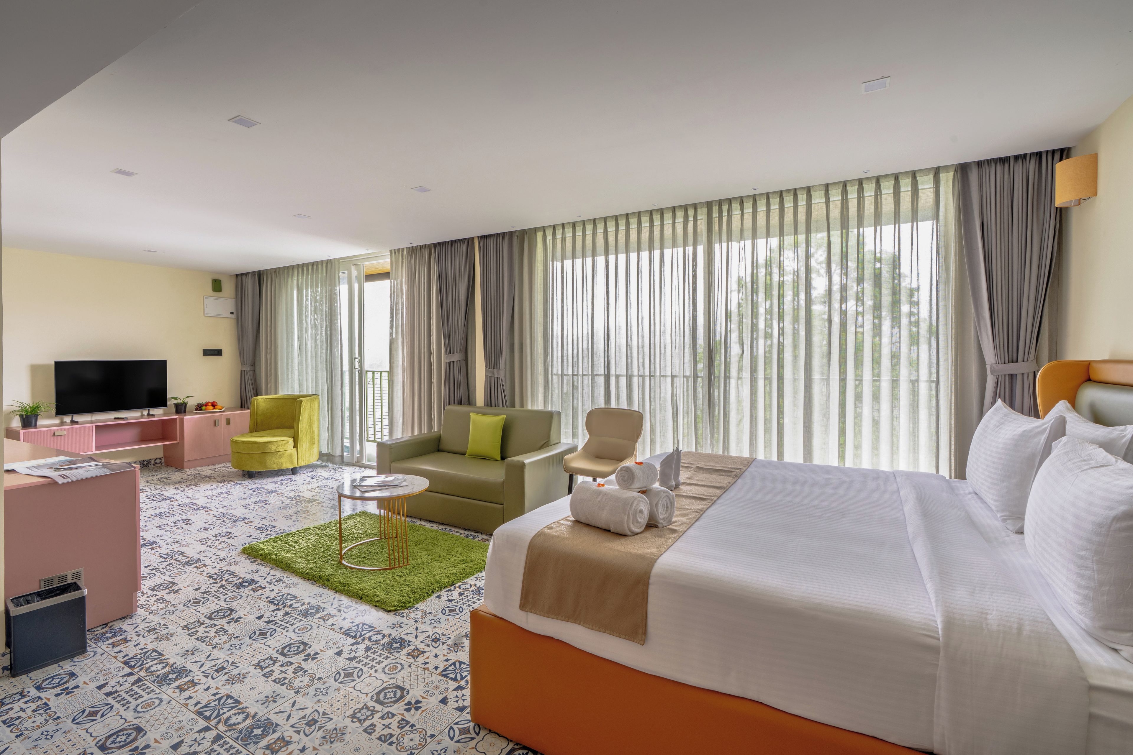 Una habitación de hotel con cama, sofá, televisión y escritorio.