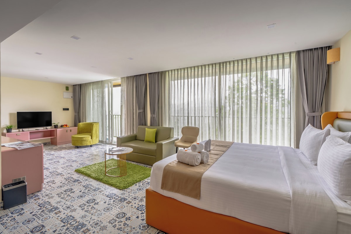 A hotel room with a bed, a sofa, a TV, and a desk.