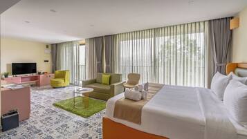 Una habitación de hotel con cama, sofá, televisión y escritorio.