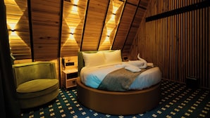 Una cama redonda en una habitación con paredes de madera inclinada y un suelo estampado.