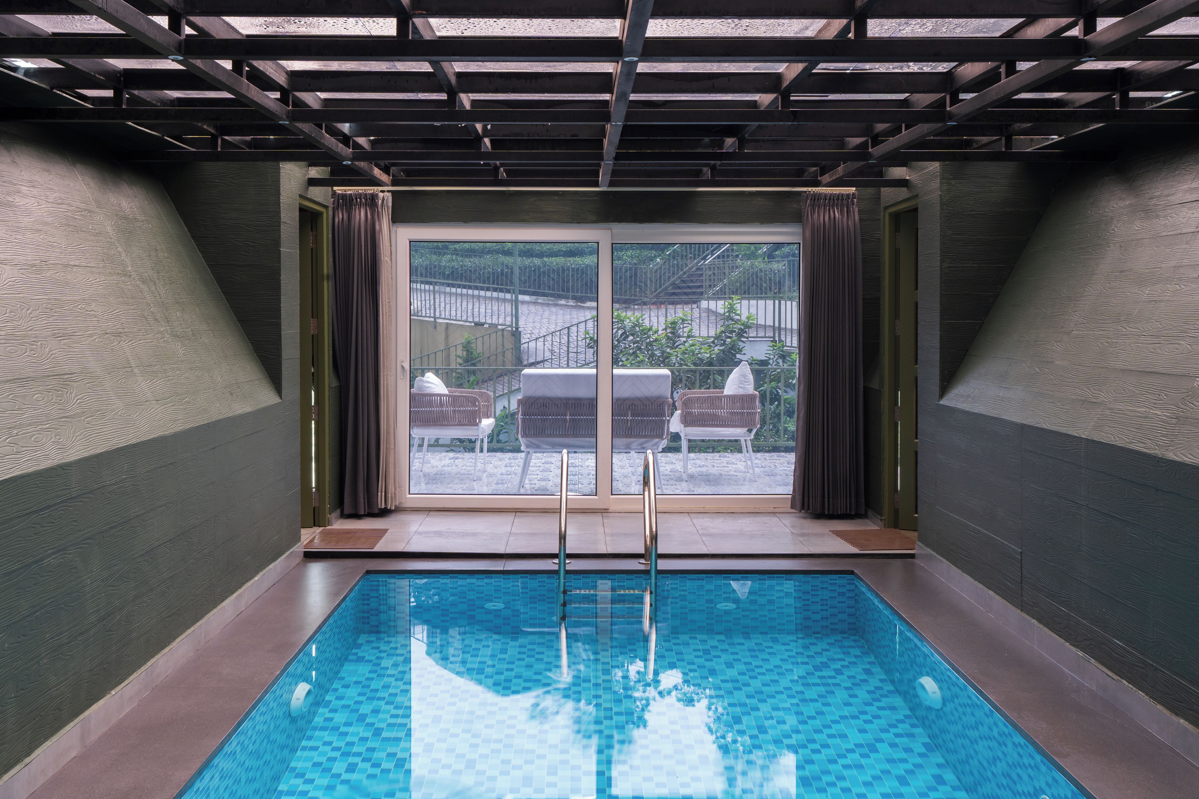 An indoor swimming pool with a clear view of the outside through large glass doors.