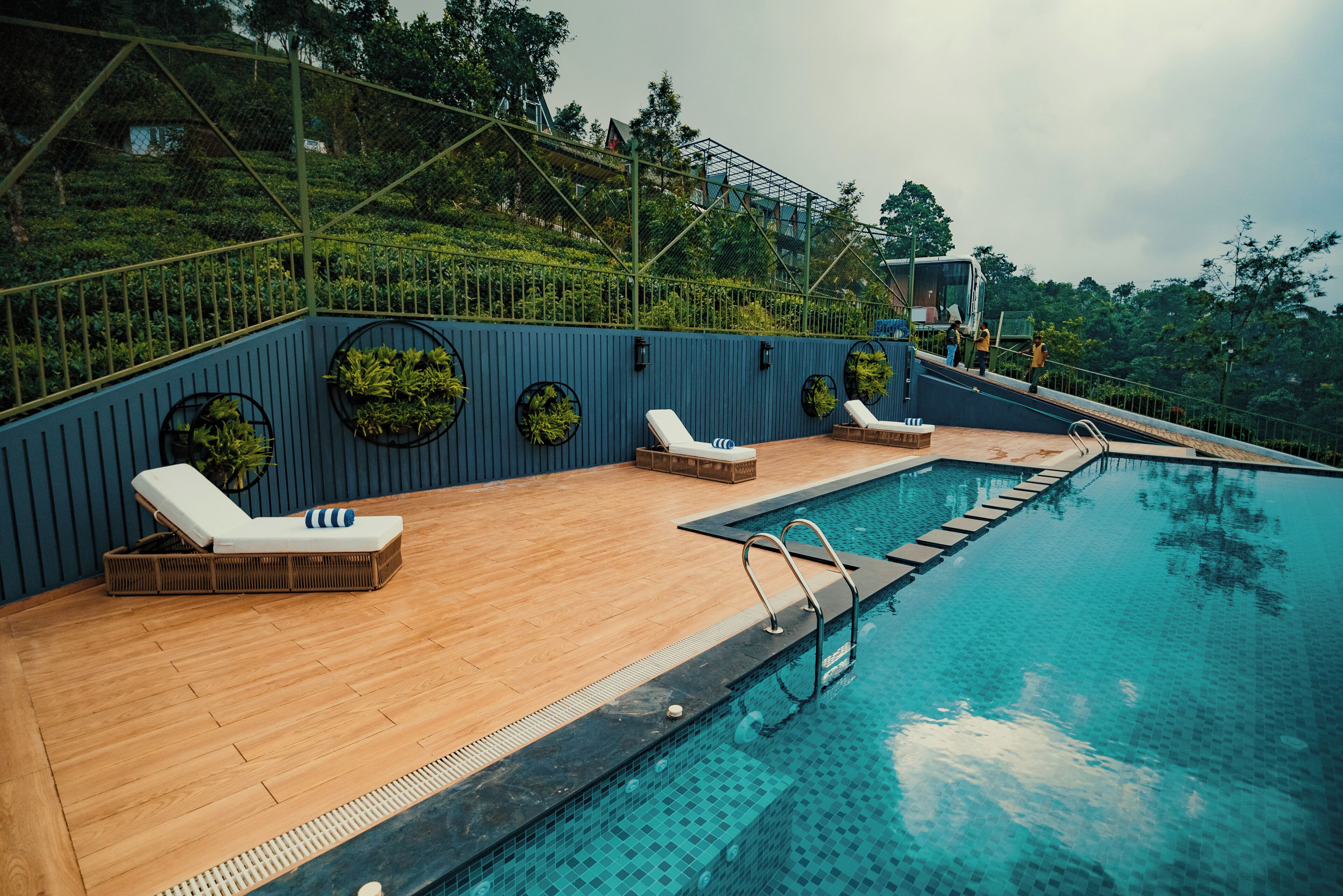 Zona de piscina con sillones de descanso y una terraza de madera.