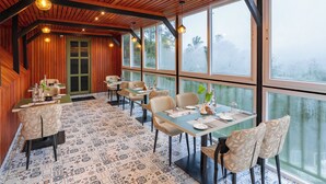 Un restaurante con vigas de madera en el techo, ventanas amplias y baldosas de suelo con diseños.