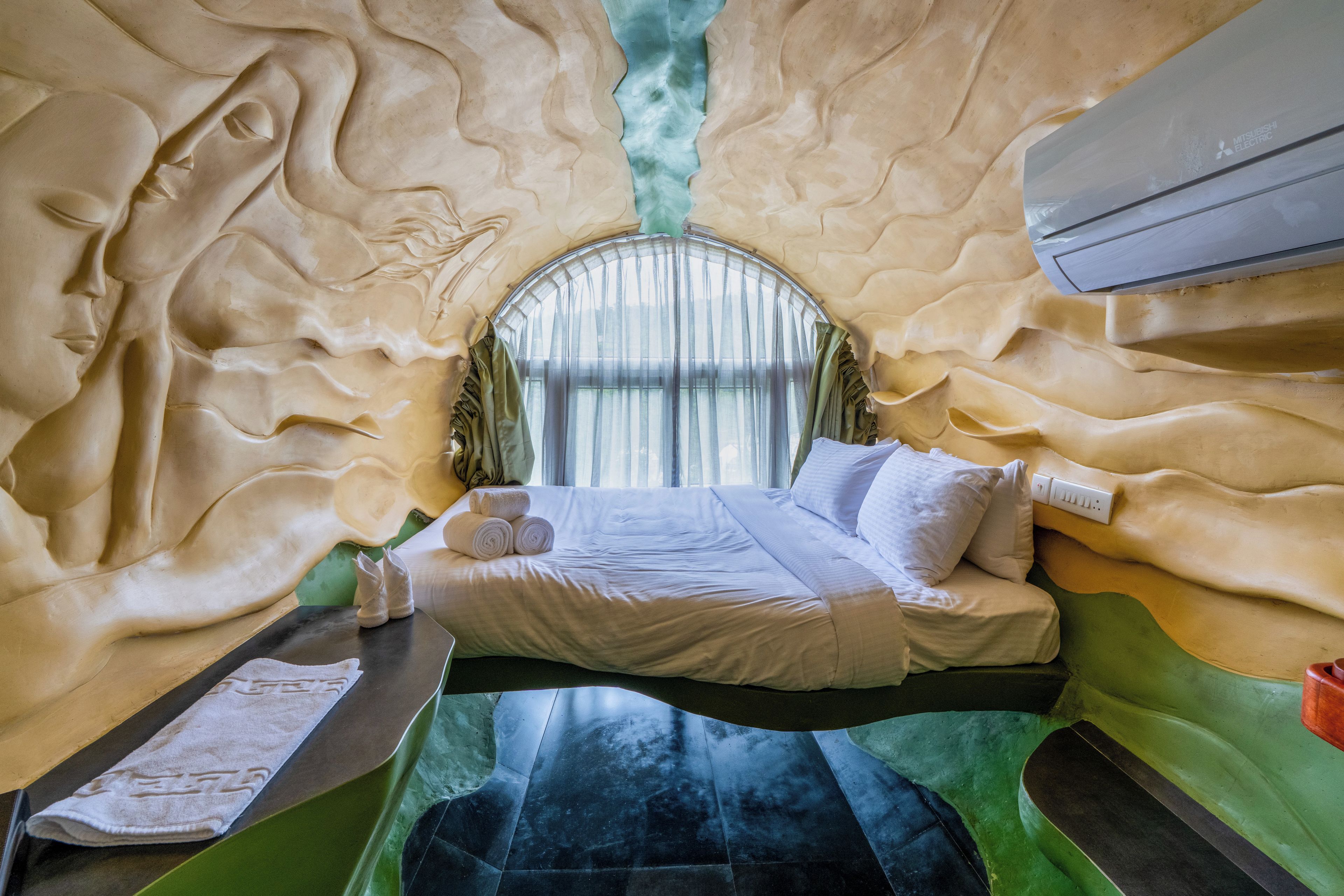 A room with a bed, a window, and a wall-mounted air conditioner.