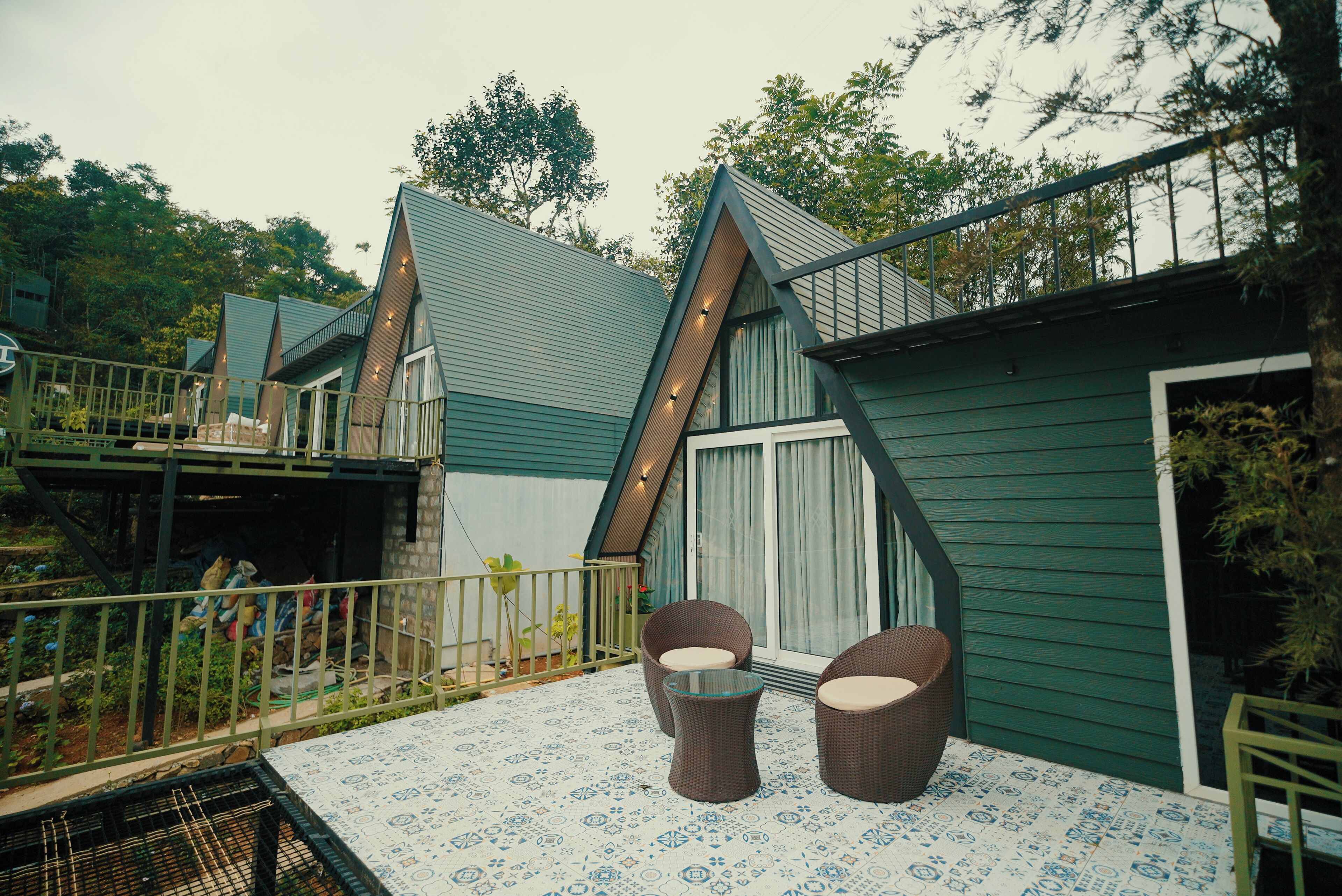 A residential property with a balcony, two wicker chairs, and a patterned floor.